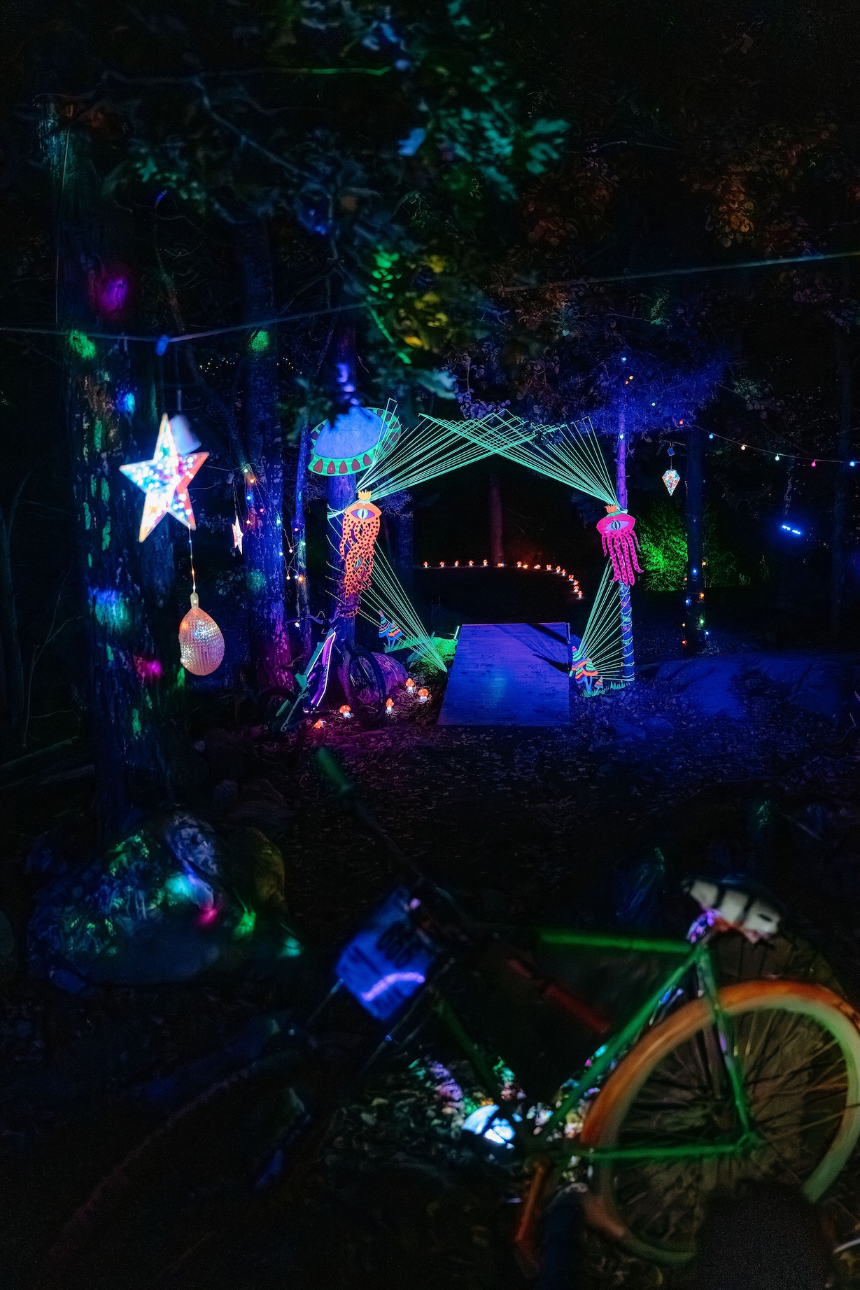 Skulpturer i neon upplysta i en bike park i mörkret.