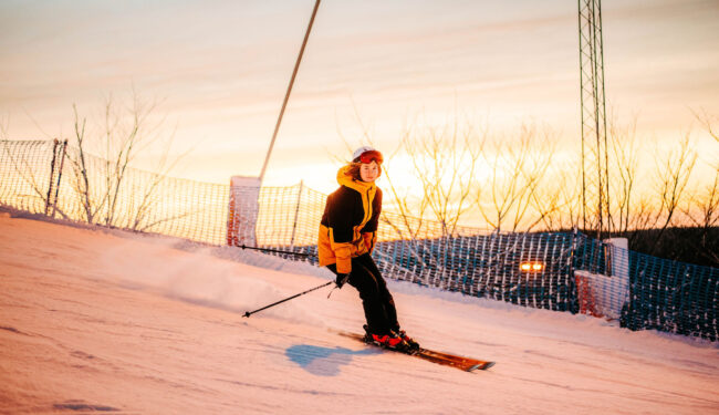 En tjej åker skidor i en backe med härlig vintersol.