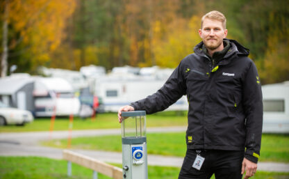 bilden visar en man, i bakgrunden syns grön yta och husvagnar på en camping